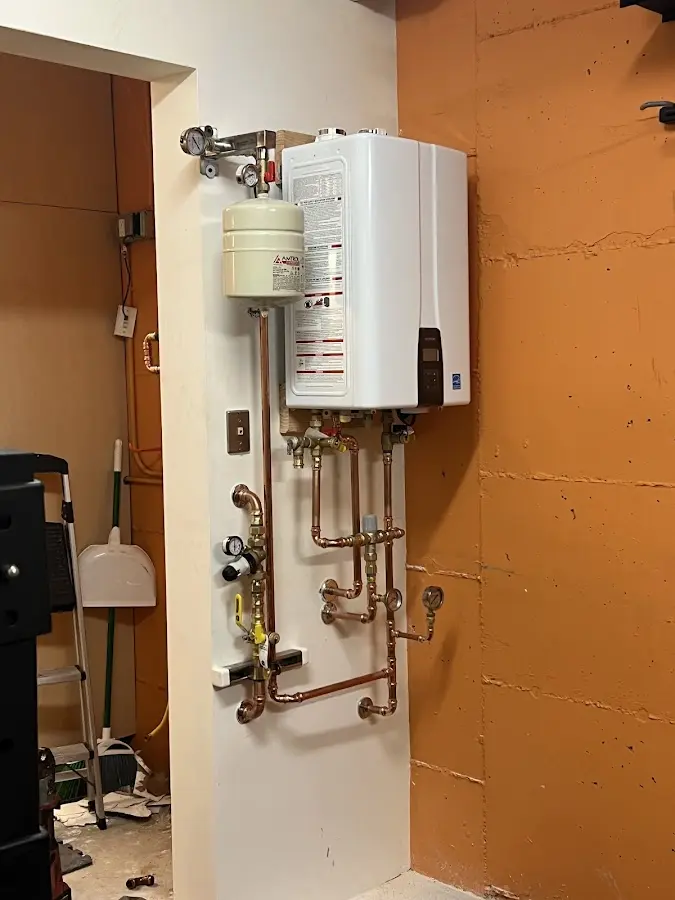 Plumbing technician inspecting water heater connections in Swansea